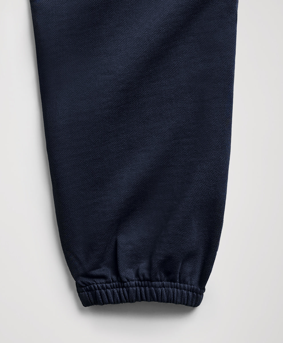 Close-up of a dark navy blue fabric pant leg with an elasticized cuff, shown against a light gray background.