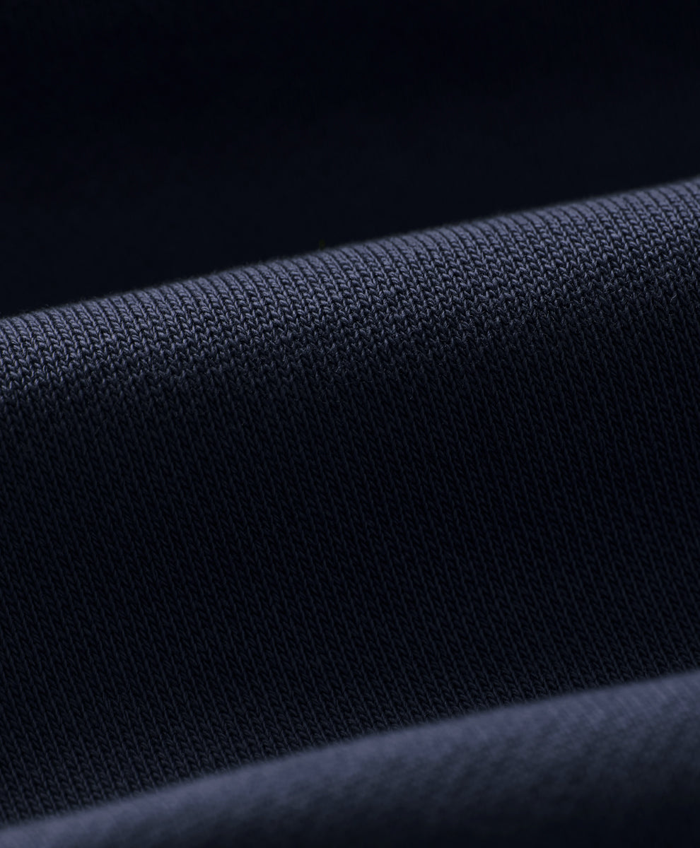Close-up of dark navy blue knit fabric with a fine ribbed texture and soft folds.