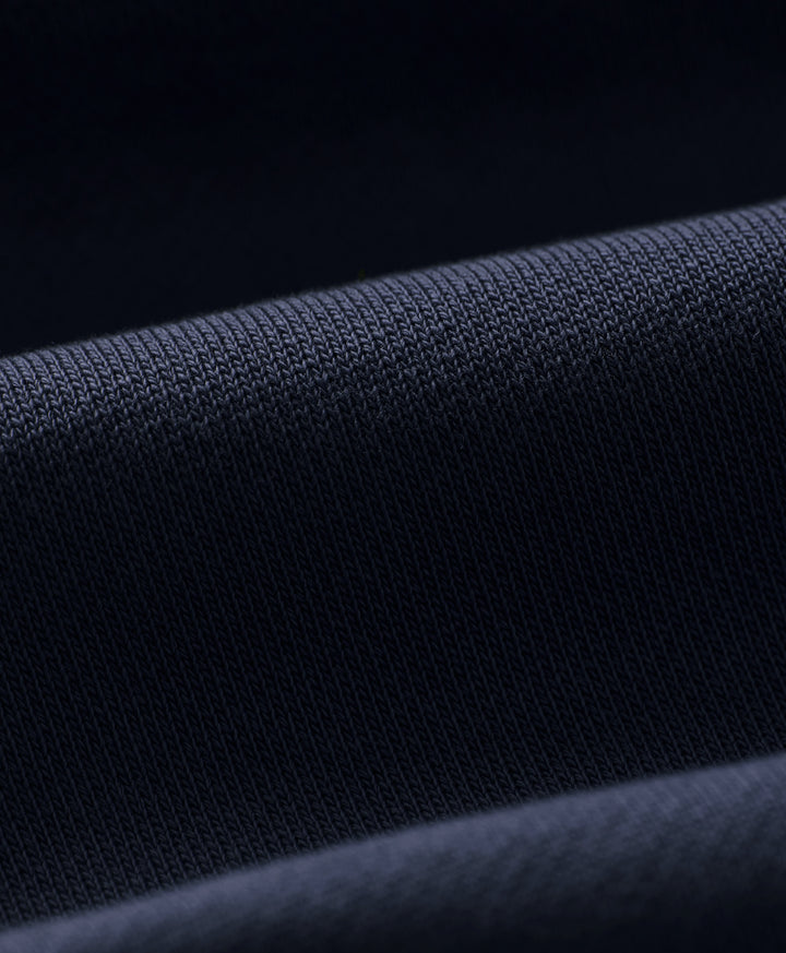 Close-up of dark navy blue knit fabric with a fine ribbed texture and soft folds.
