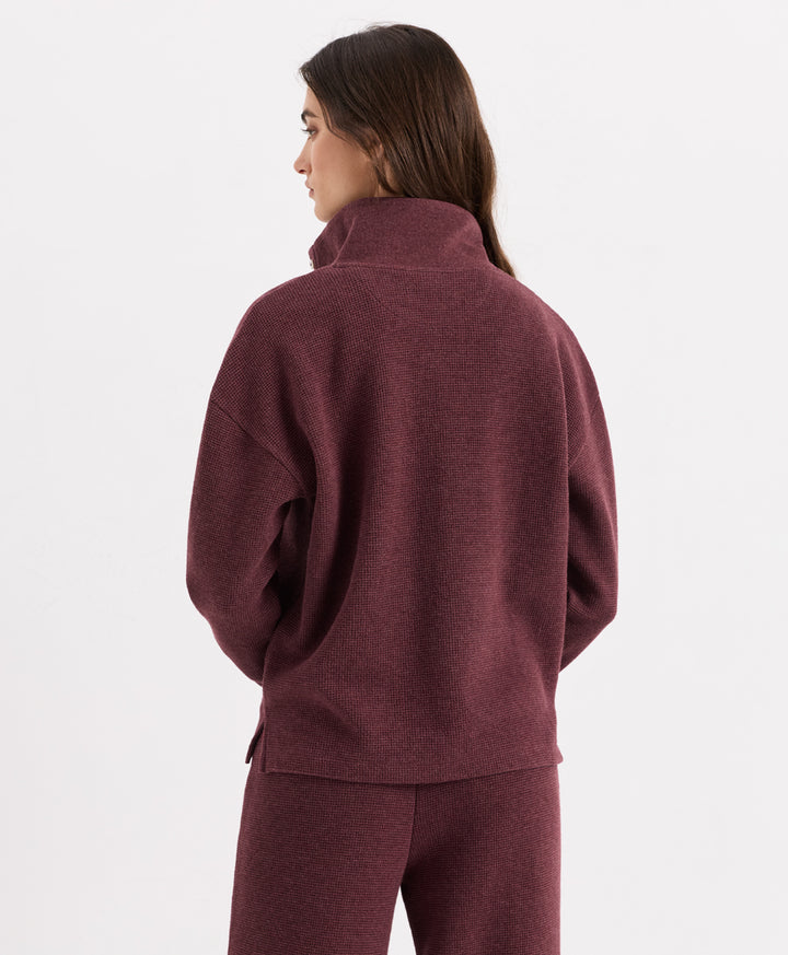 A woman shown from the back wearing a merlot heather henley and matching pants against a clean white studio background.