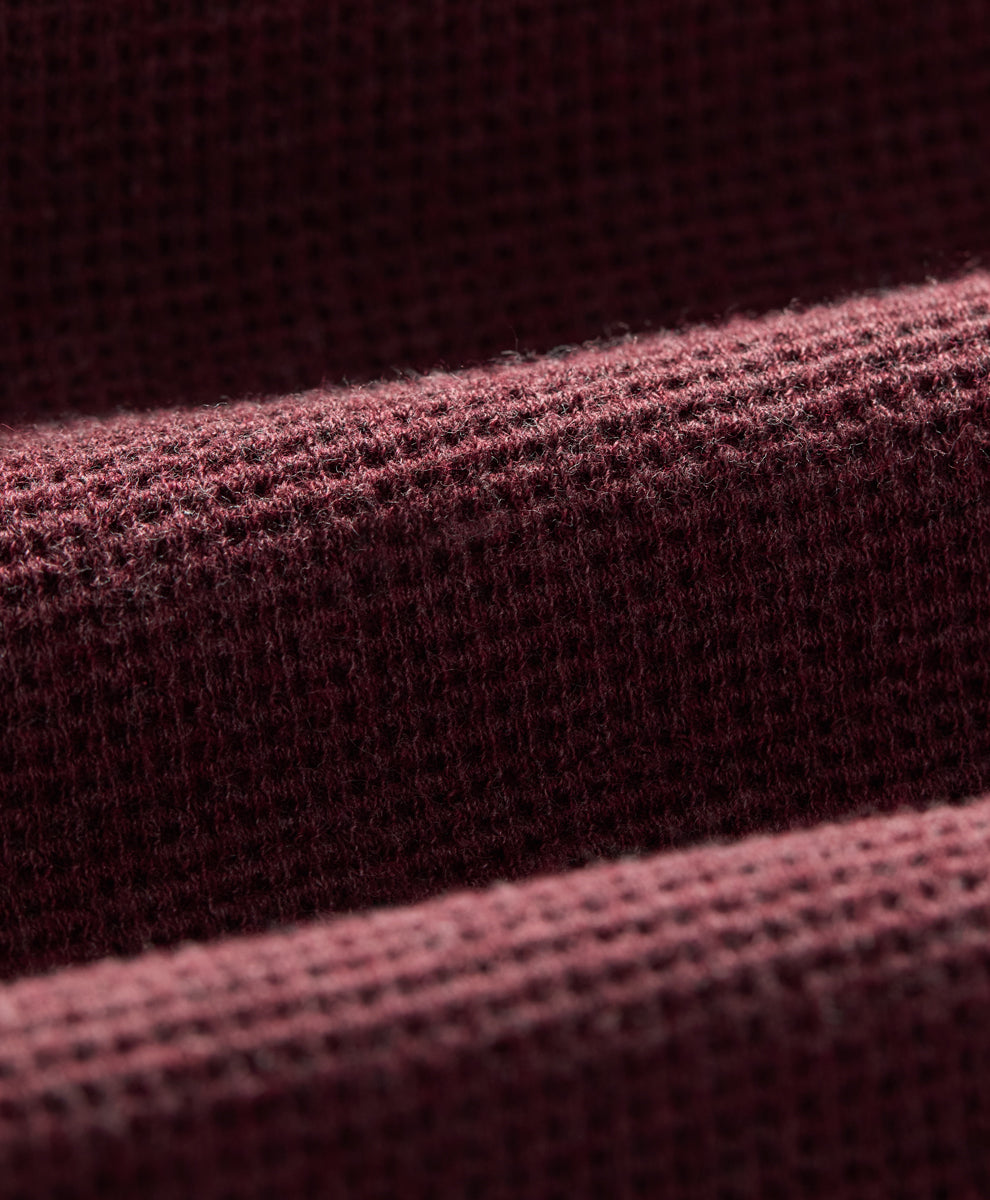 Close-up of a textured knit fabric in a merlot heather, showing the detailed weave and soft folds.
