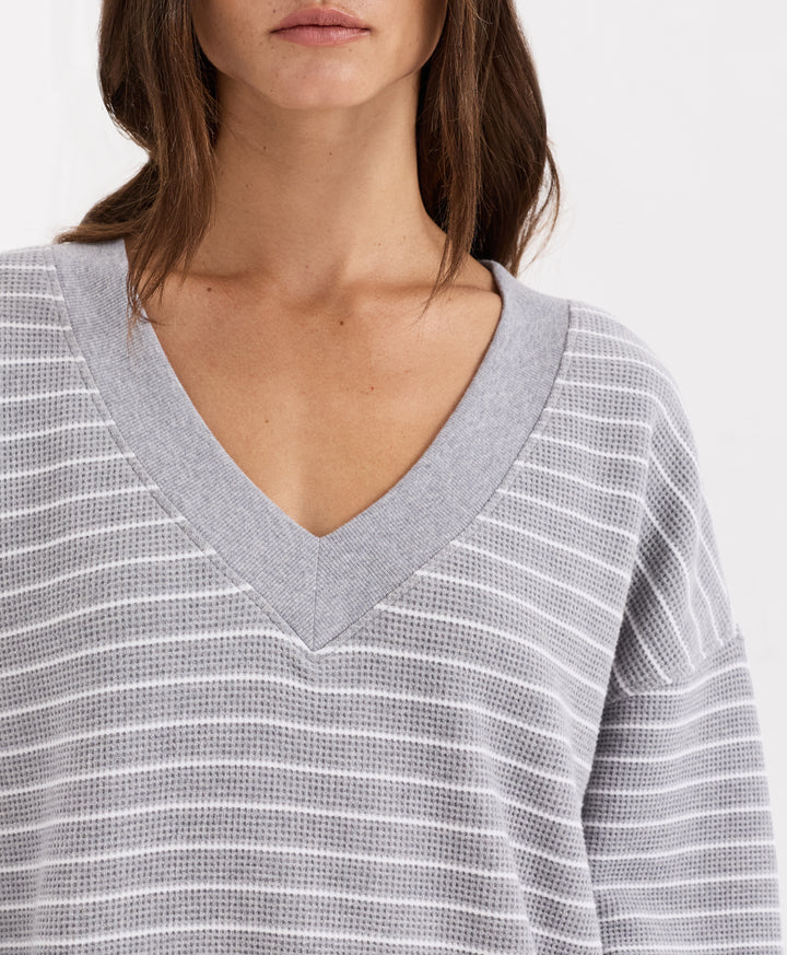 Close-up of a woman wearing a gray and white horizontally striped waffle-knit V-neck top.