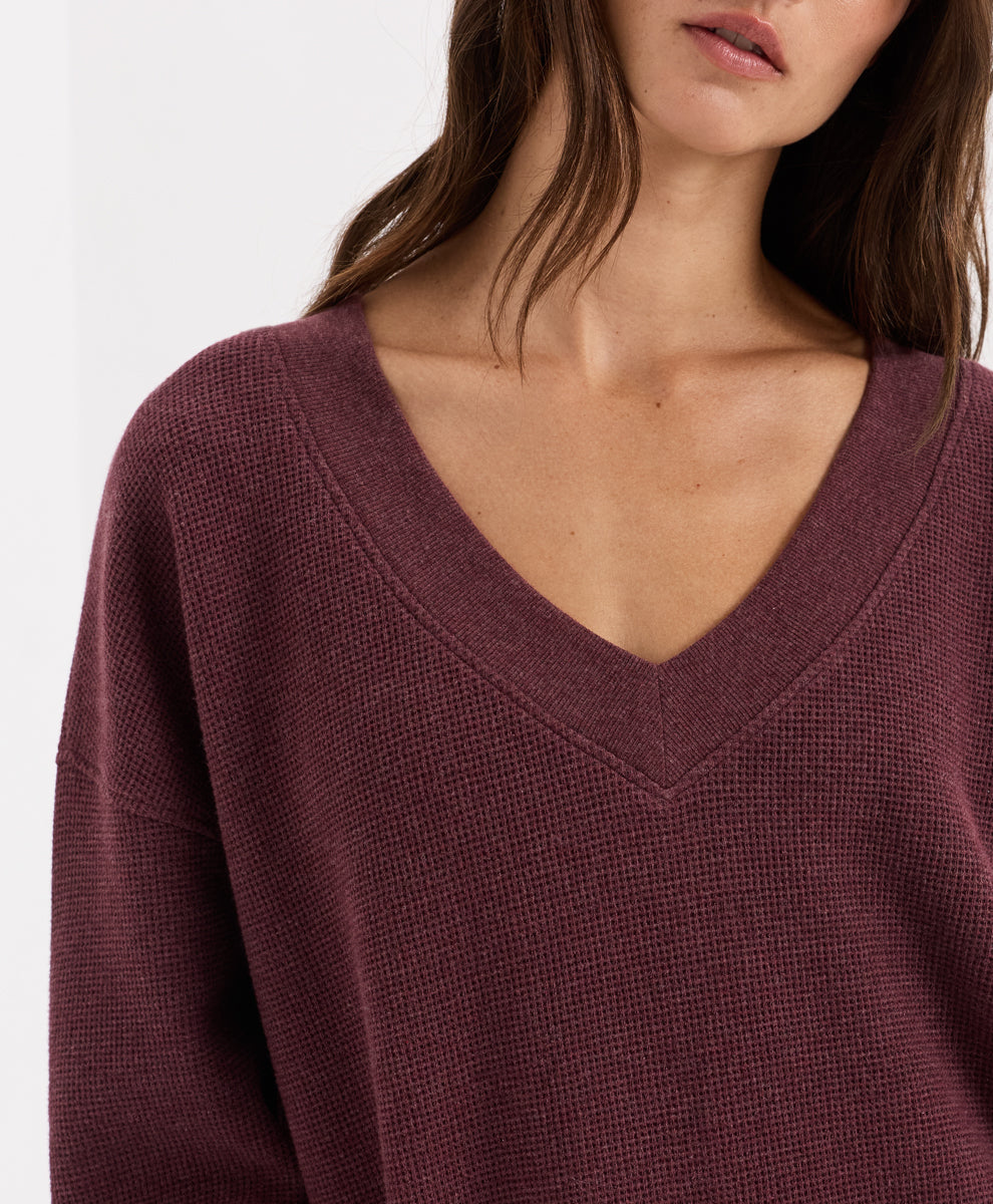 Close-up of a woman wearing a waffle-knit V-neck top in a merlot heather against a plain light background.
