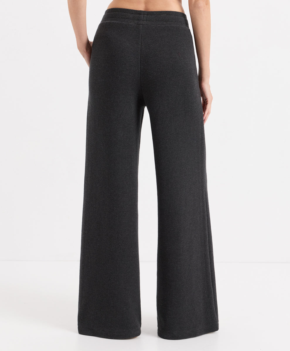 A person shown from the back wearing dark charcoal heather wide-leg pants against a clean white studio background.