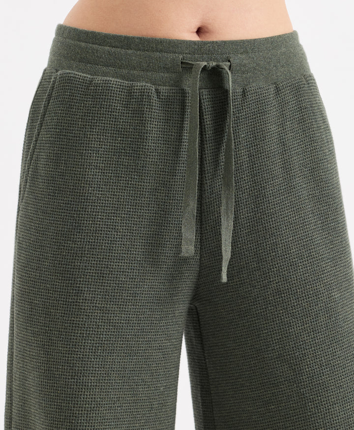Close-up of a person wearing textured dusted green heather wide-leg pants with a matching drawstring waistband, shown against a plain light background.