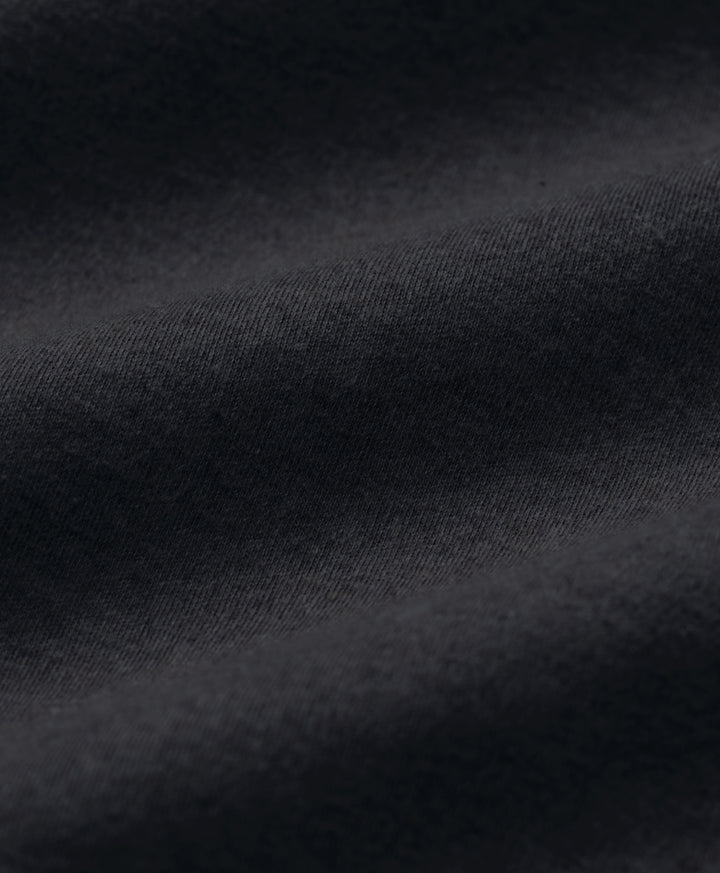 Close-up of dark charcoal heather fabric with soft folds and a fine woven texture.