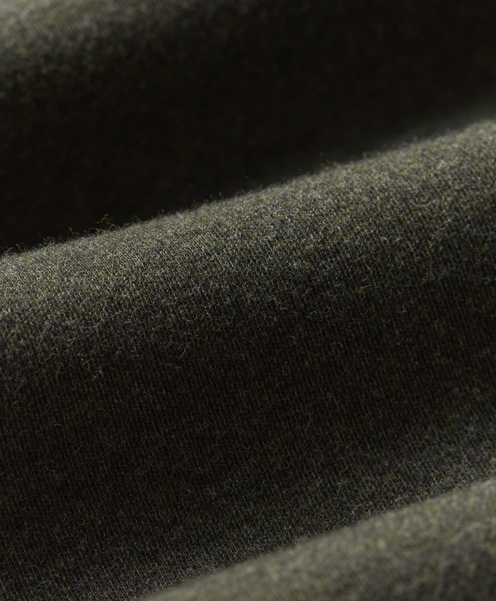 Close-up of loden green fabric with a soft, slightly fuzzy texture and draped folds.