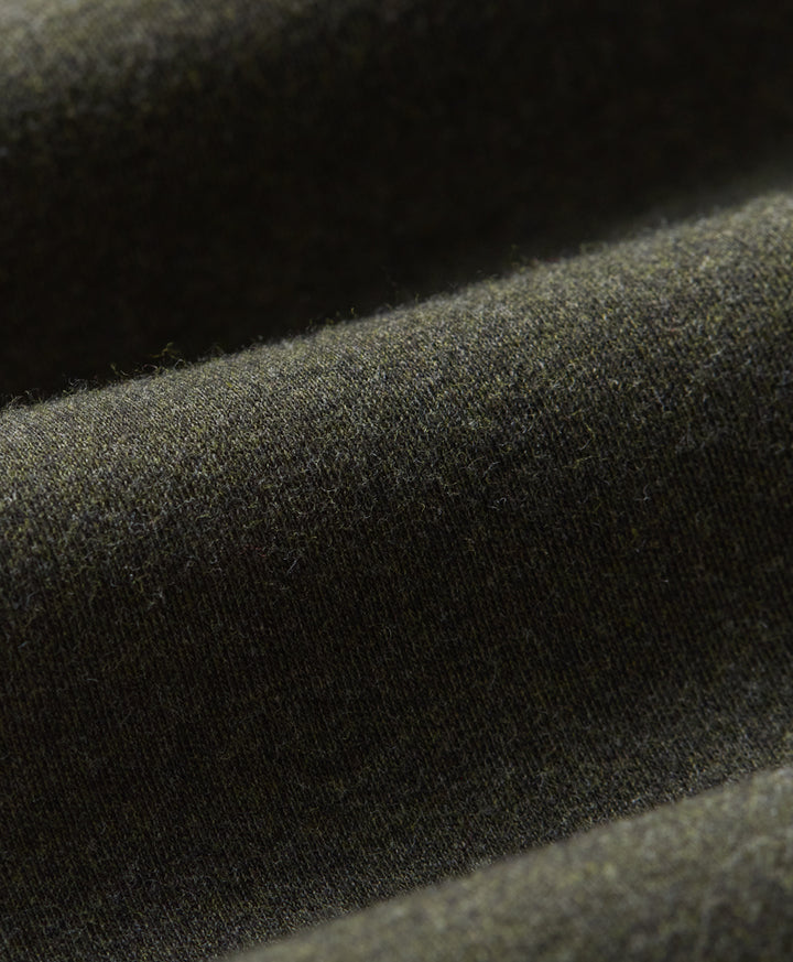 Close-up of loden green fabric with a soft, slightly fuzzy texture and draped folds.