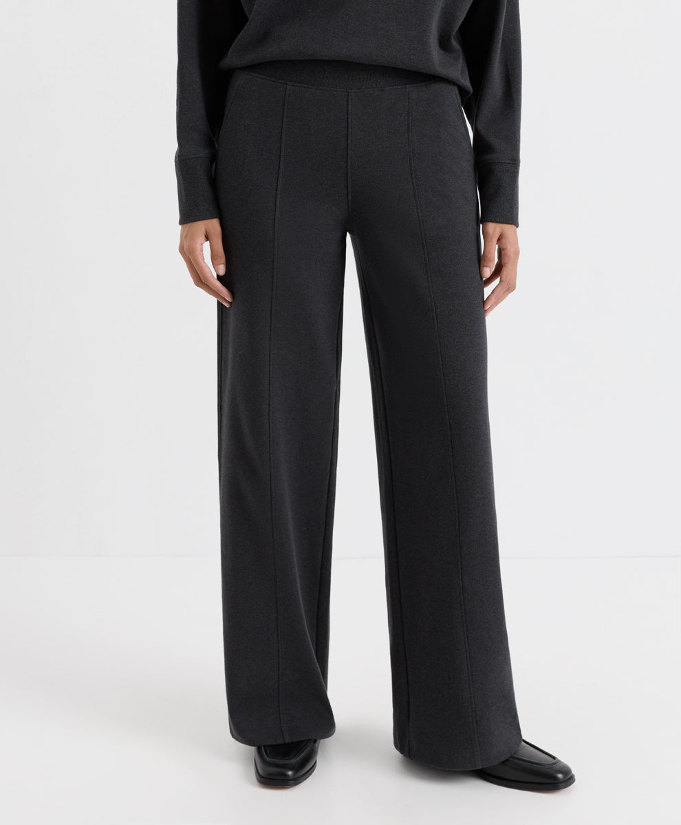 A model wearing dark charcoal heather wide-leg trousers, a matching long-sleeve top, and black leather shoes, shown from the waist down against a plain white studio background.