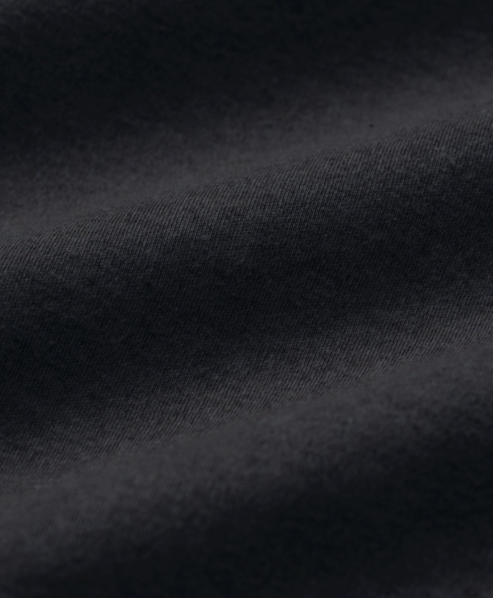 Close-up of dark charcoal heather fabric with soft folds and a fine woven texture.