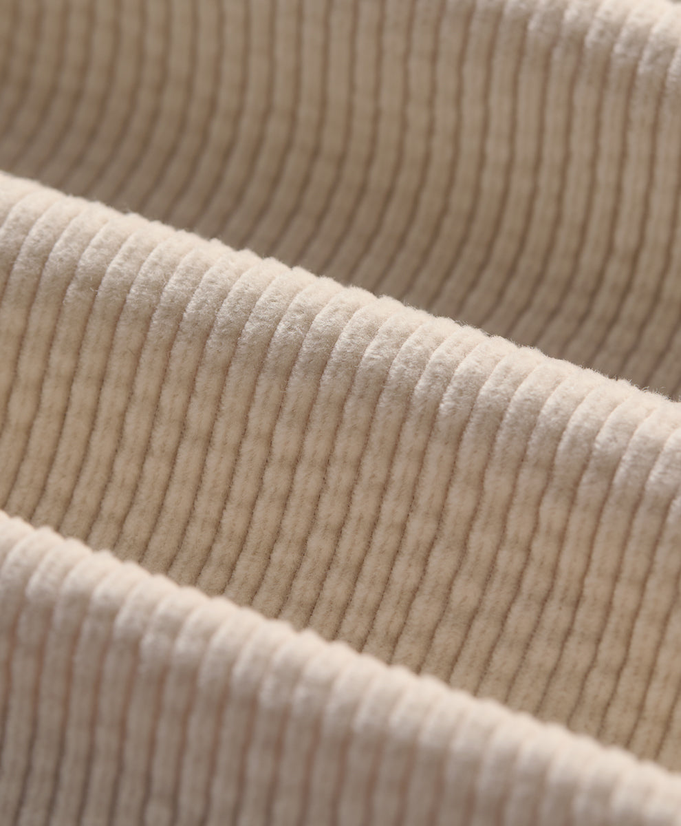 Close-up of corduroy fabric in parchment, showing the texture and folds.