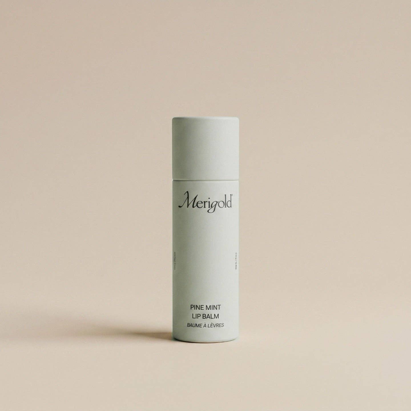 Lip balm container with 'Merigold' branding on a beige background