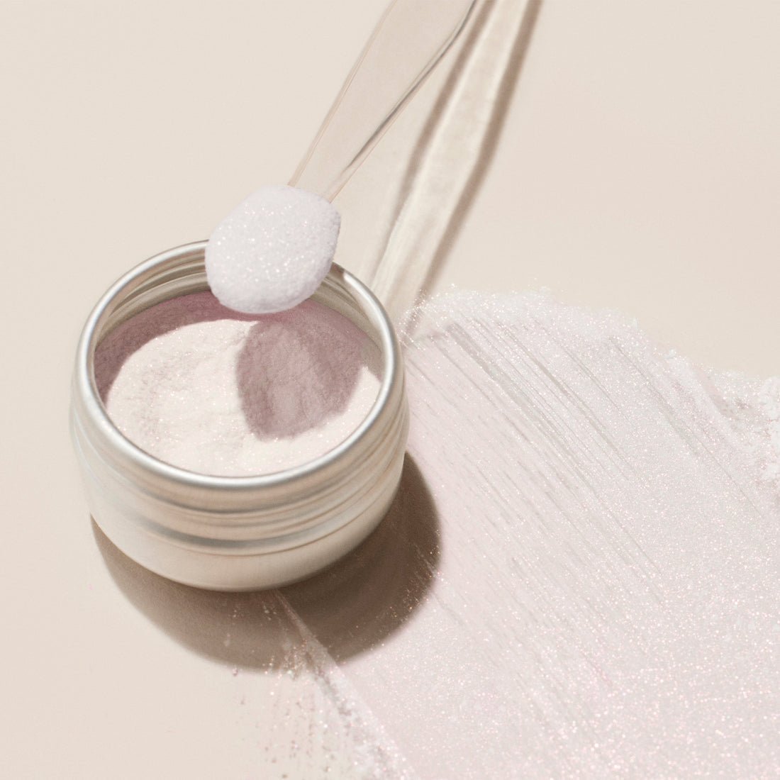 Jar of pink effect glazed powder with a spoonful being lifted, on a light beige background