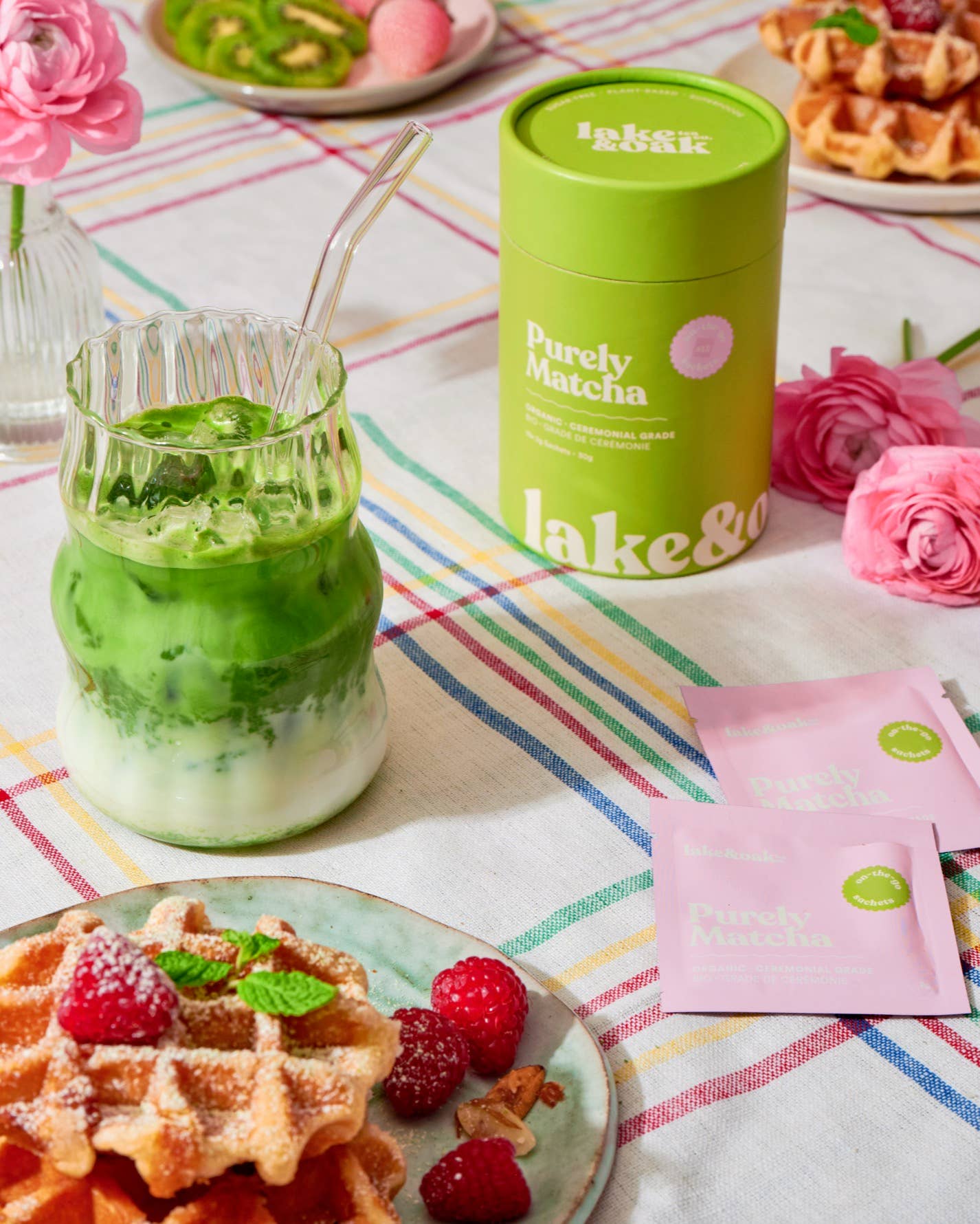 Matcha green tea drink with waffles and berries on a colorful tablecloth.