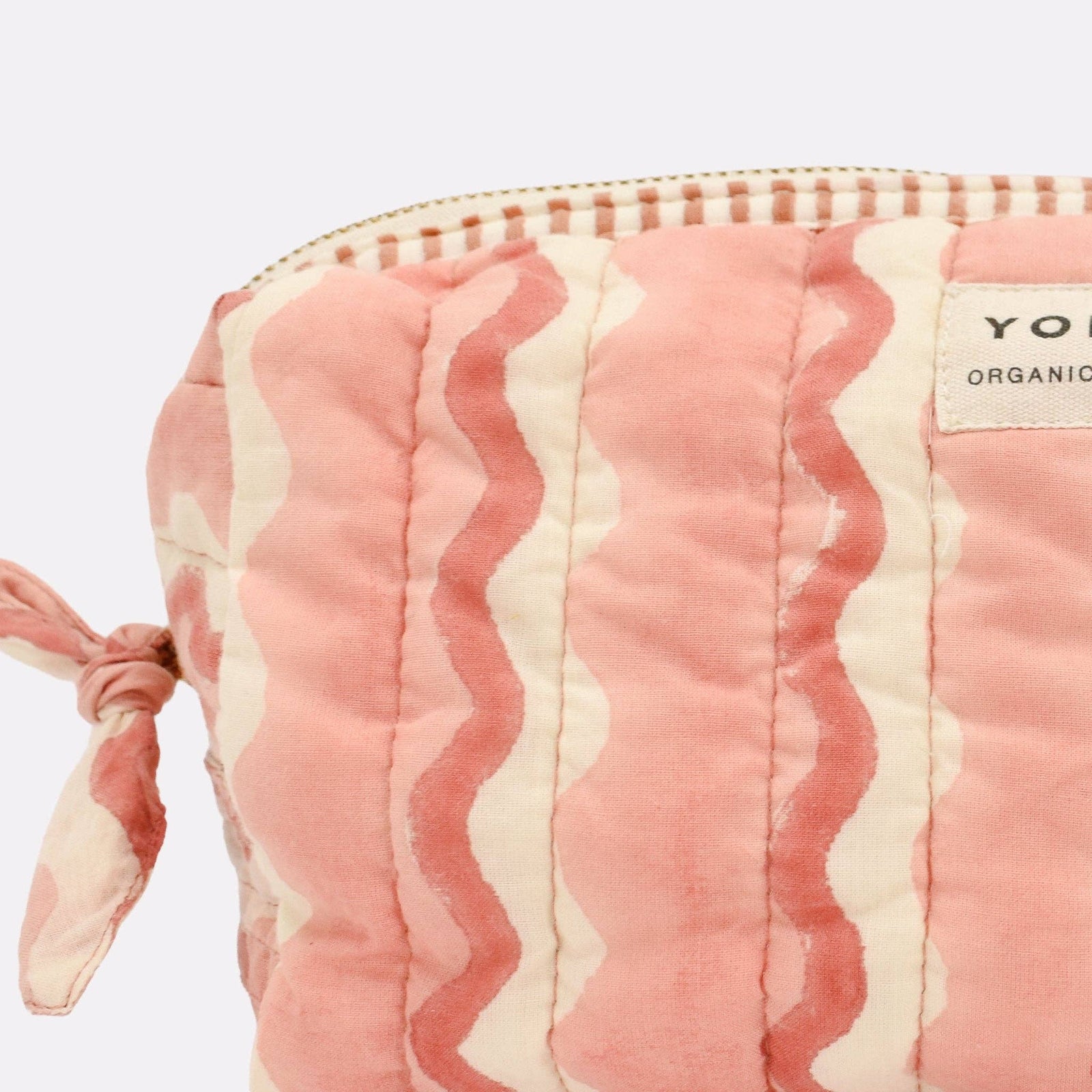 Pink and white striped pouch with a visible brand label on a light purple background