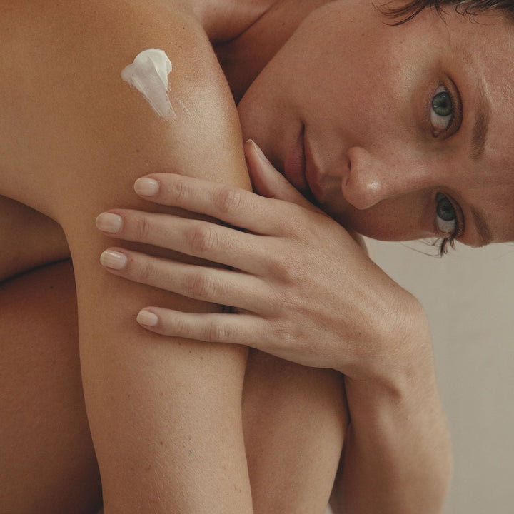 Woman applying lotion to her shoulder w.