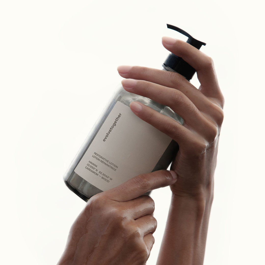 Hand holding a evolvetogether restorative lotion with a pump on a white background