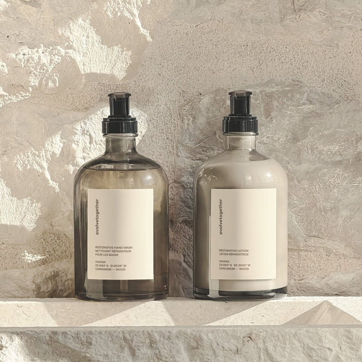Two bottles of soap and lotion on a stone surface with a neutral background