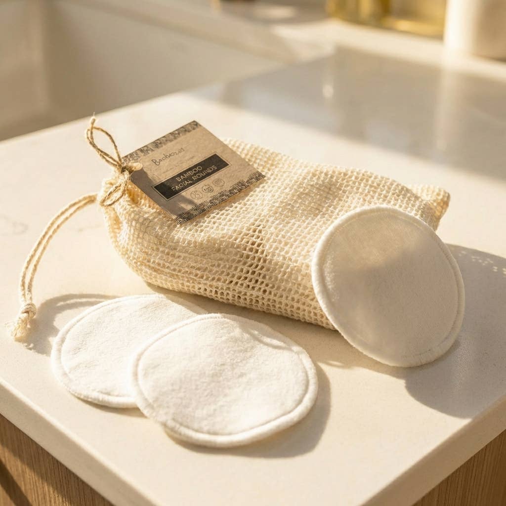 Set of reusable bamboo pads and mesh bag on a bathroom counter