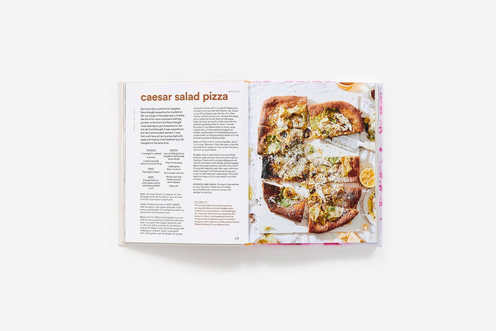 Open book showing a recipe for Caesar salad pizza on a white background