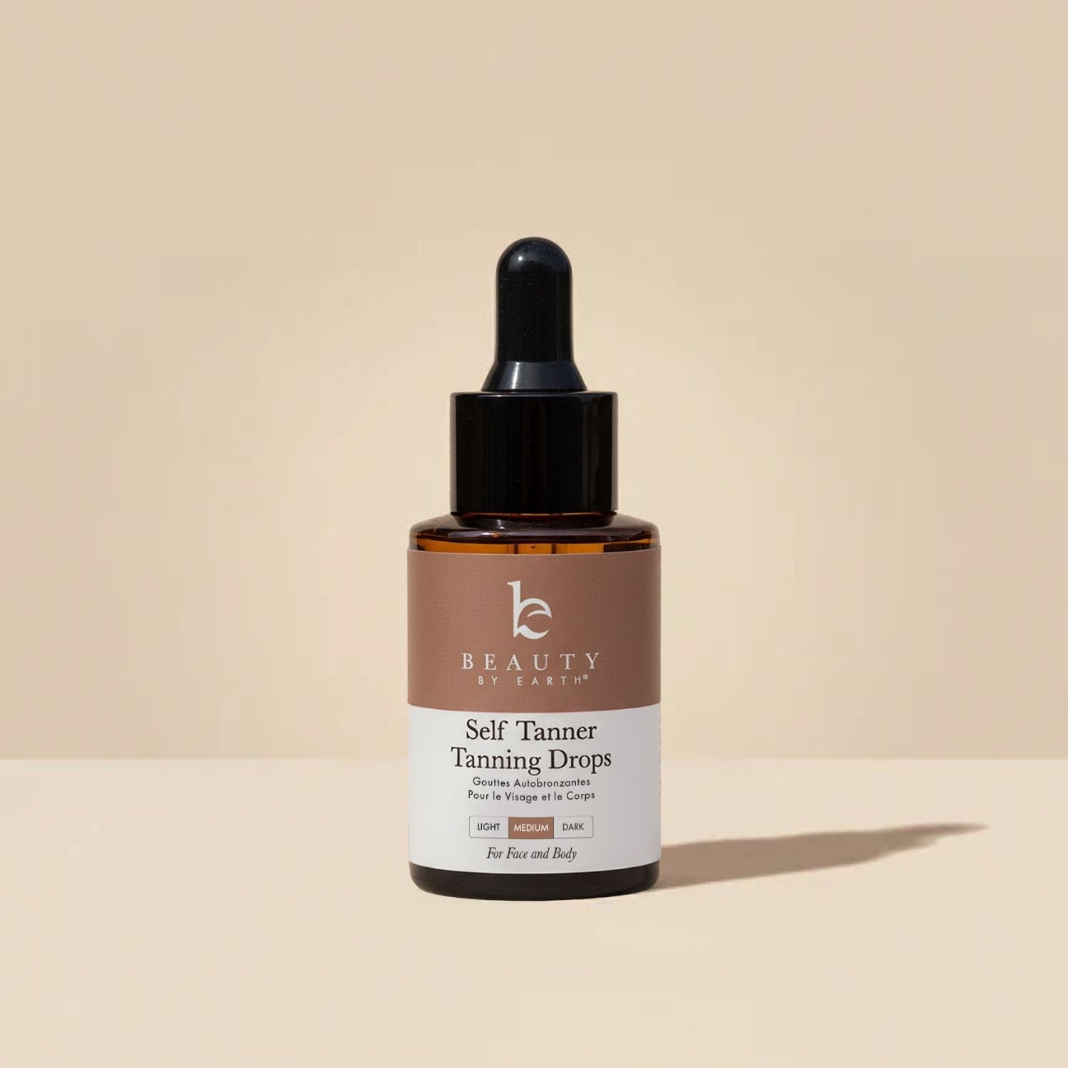 Bottle of 'Beauty by Earth' self Tanner tanning drops on a beige background