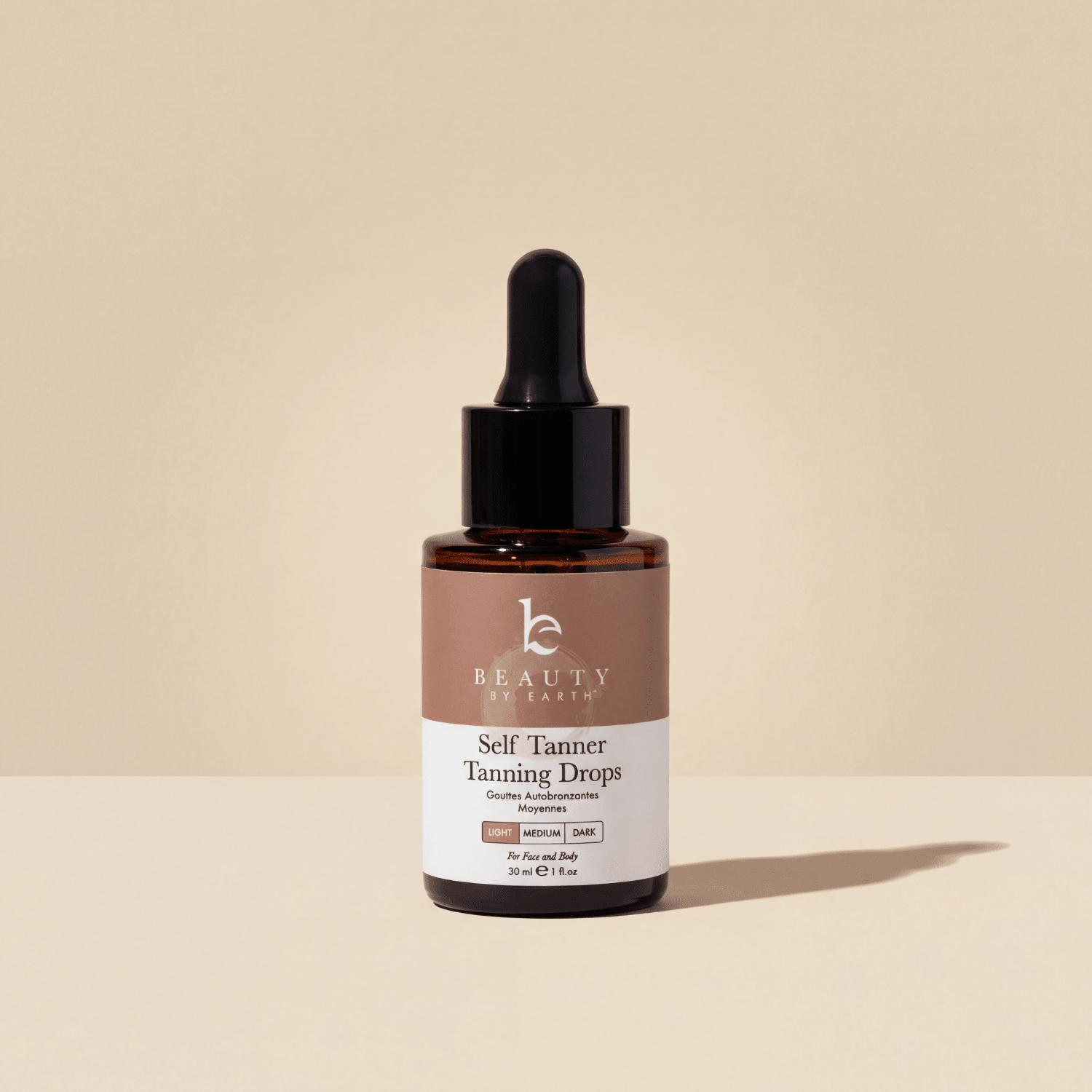Bottle of Beauty by Earth Self Tanner Tanning Drops on a beige background