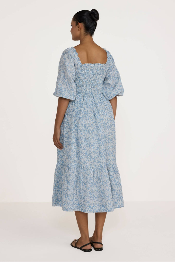 Woman wearing a Laude Label Shirred Bodice Dress in Floral on a white background
