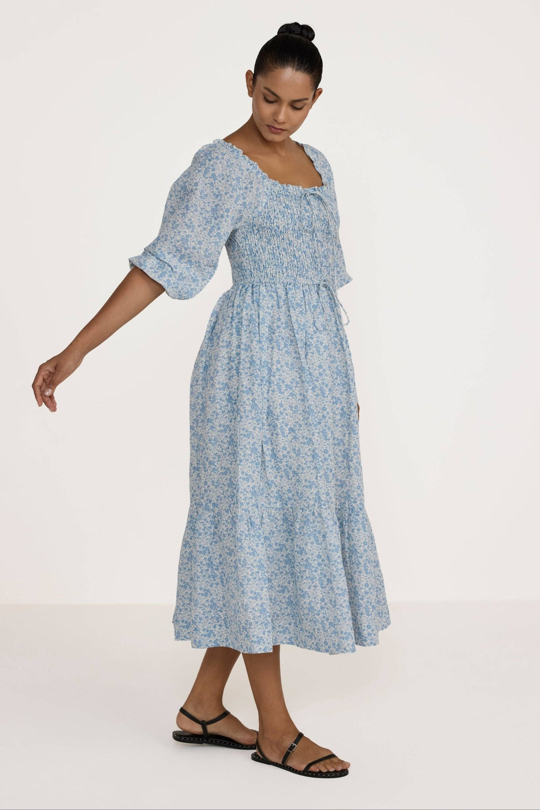 Woman wearing a Laude Label Shirred Bodice Dress in Floral on a white background