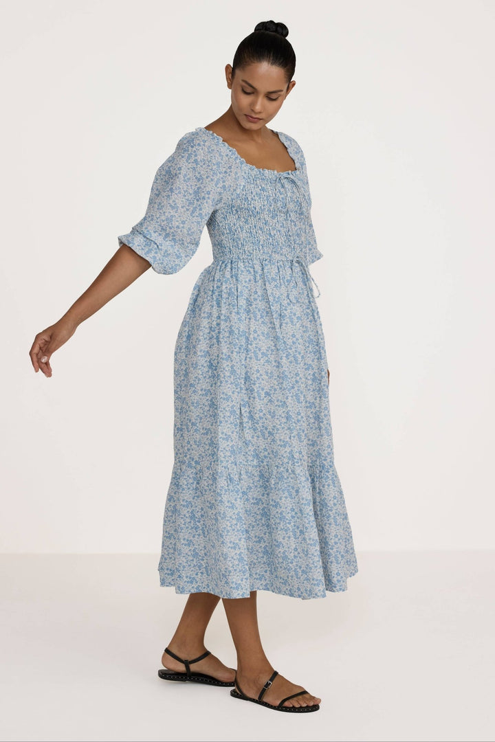Woman wearing a Laude Label Shirred Bodice Dress in Floral on a white background
