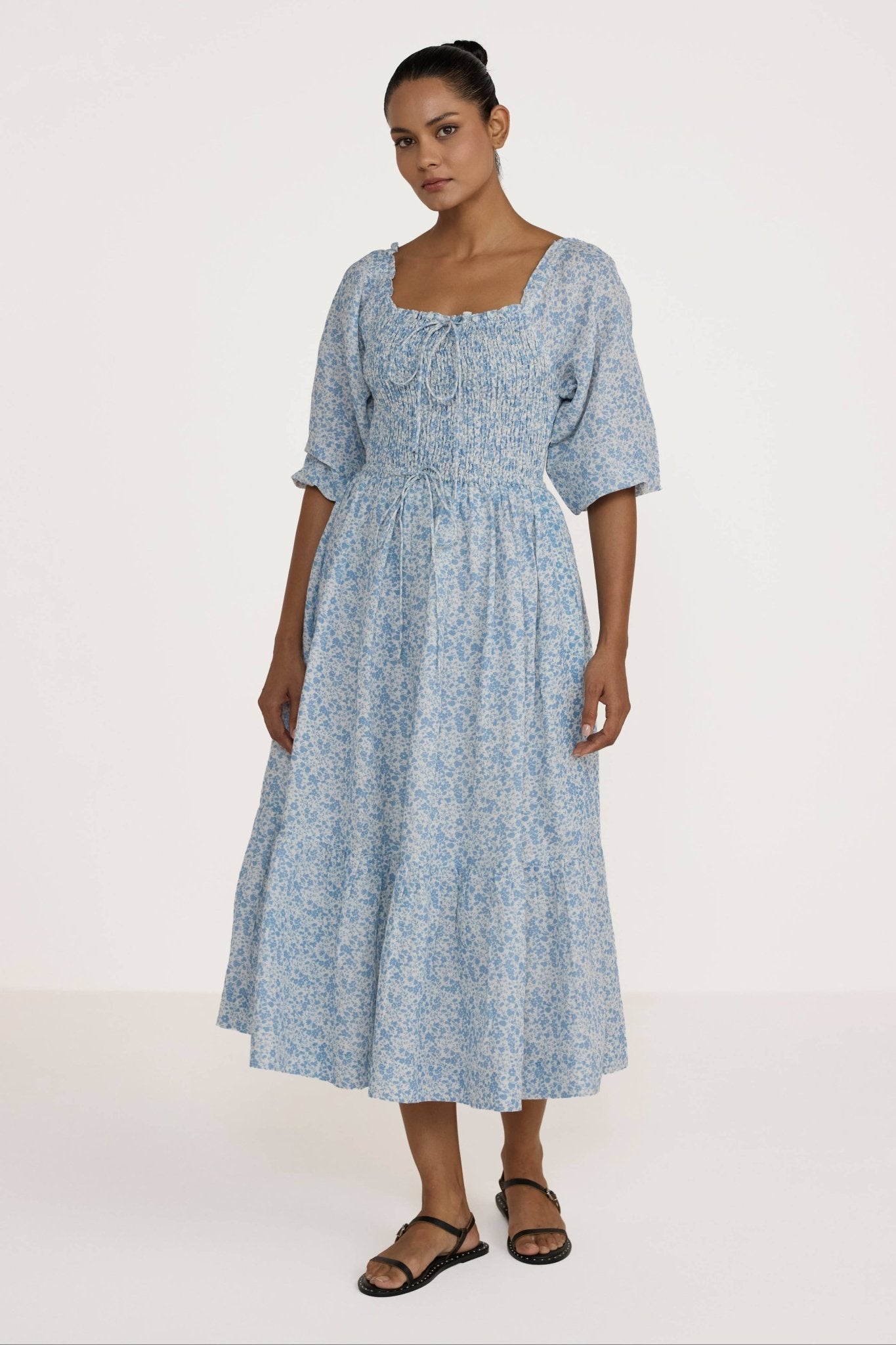 Woman wearing a Laude Label Shirred Bodice Dress in Floral on a white background