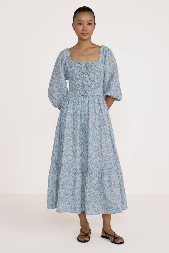 Woman wearing a Laude Label Shirred Bodice Dress in Floral on a white background