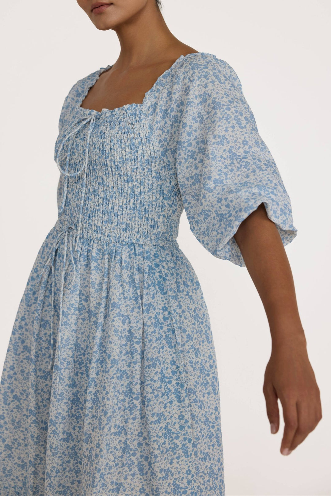 Woman wearing a Laude Label Shirred Bodice Dress in Floral on a white background