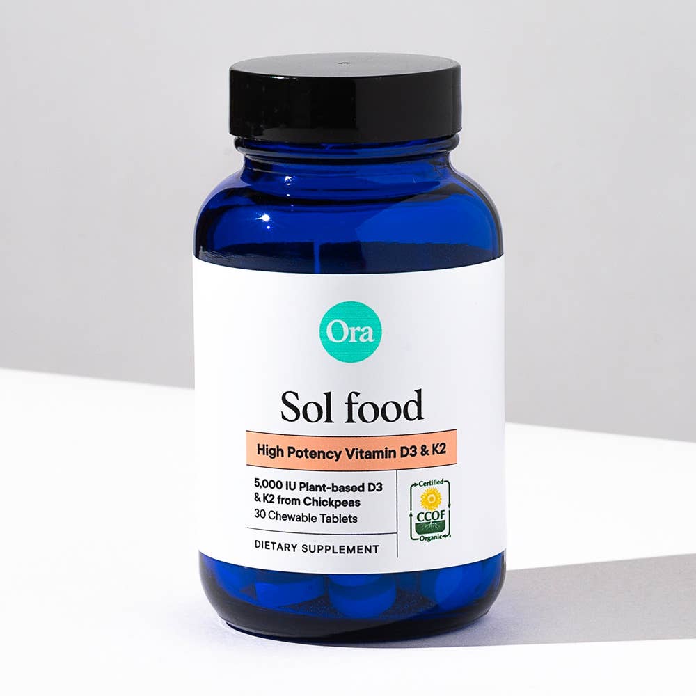 Blue supplement bottle labeled 'Ora Sol food' on a light gray background
