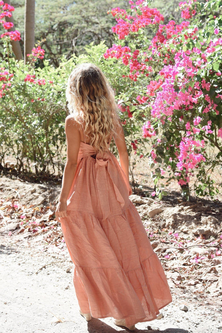 Woman in a long pink dress standing in a garden with pink flowers