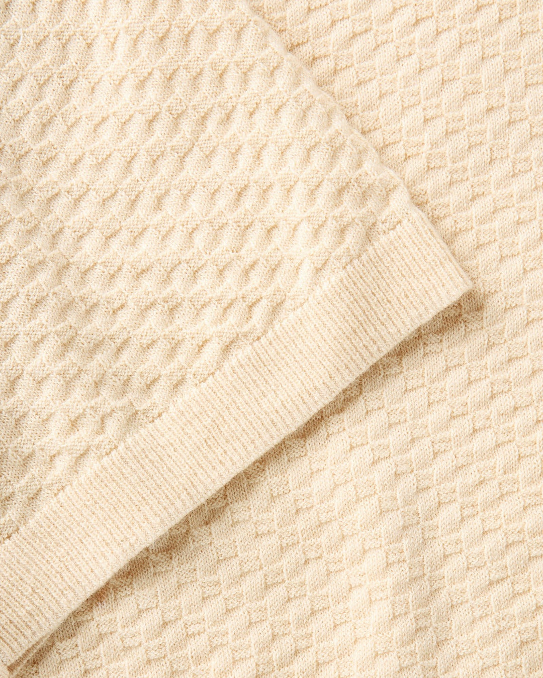 Close-up of a textured beige sweater fabric