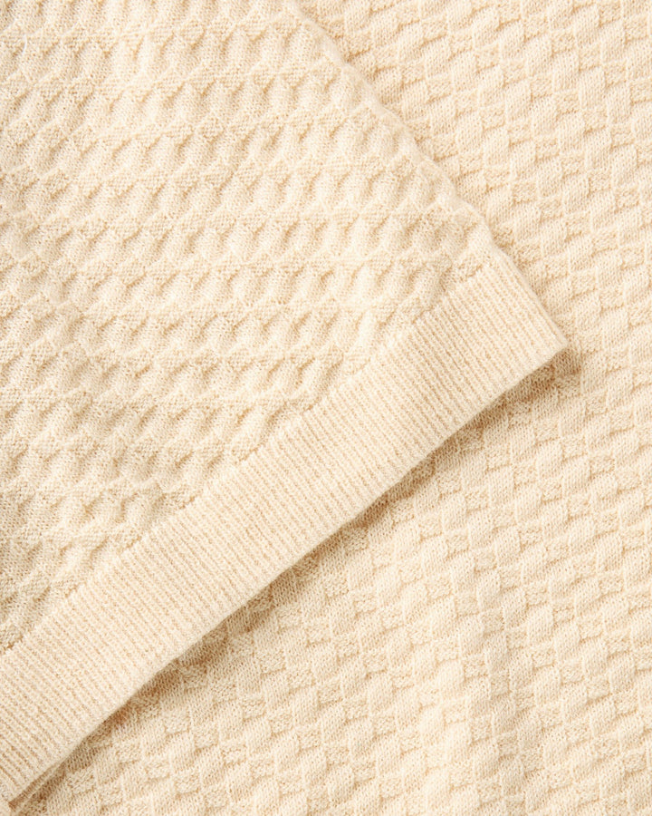 Close-up of a textured beige sweater fabric