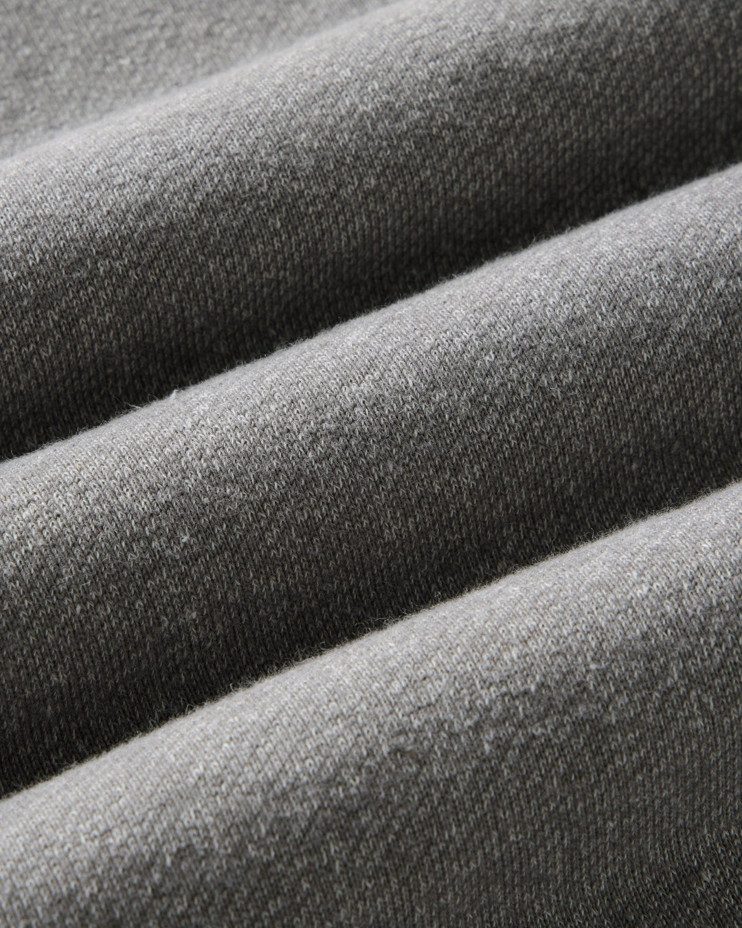 Close-up of draped gray knit fabric with a fine ribbed texture and soft folds.