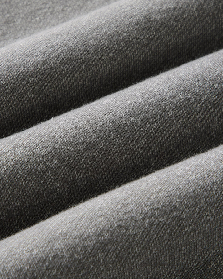 Close-up of draped gray knit fabric with a fine ribbed texture and soft folds.