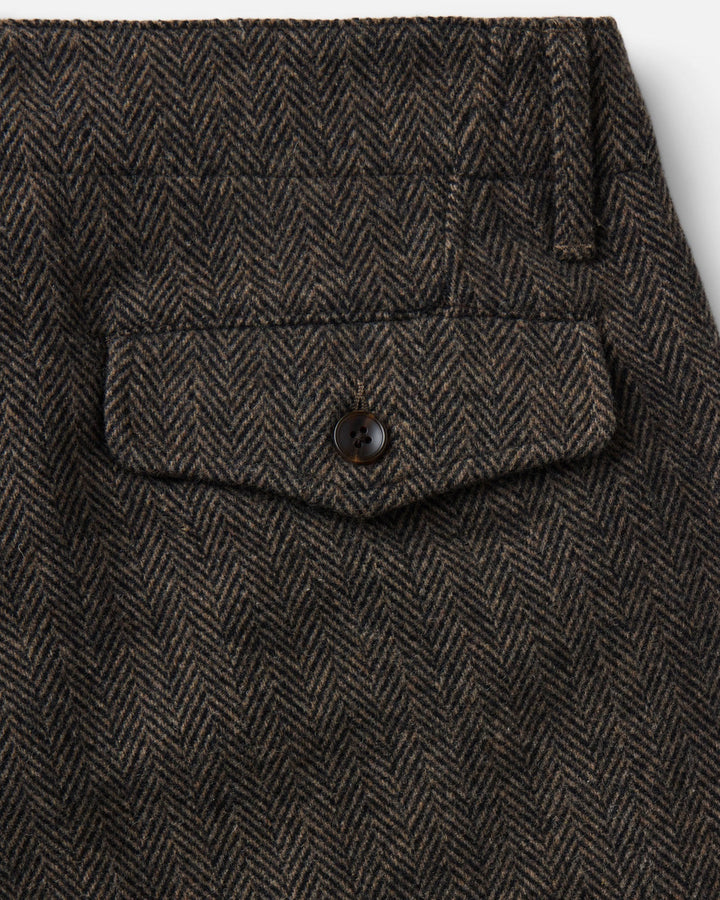 Close-up of The Carnegie Pant
in Walnut Herringbone Wool, showing a buttoned flap pocket and belt loop details.