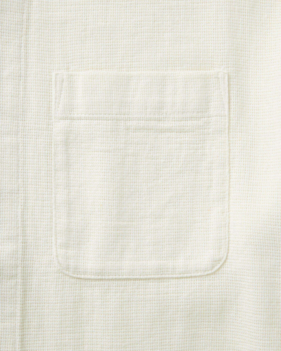 Close-up of a textured white fabric with a pocket