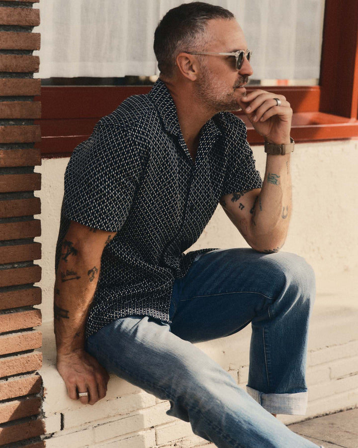 Man wearing The Davis Shirt in Indigo Raindrop Sashiko and jeans sitting against a brick wall.