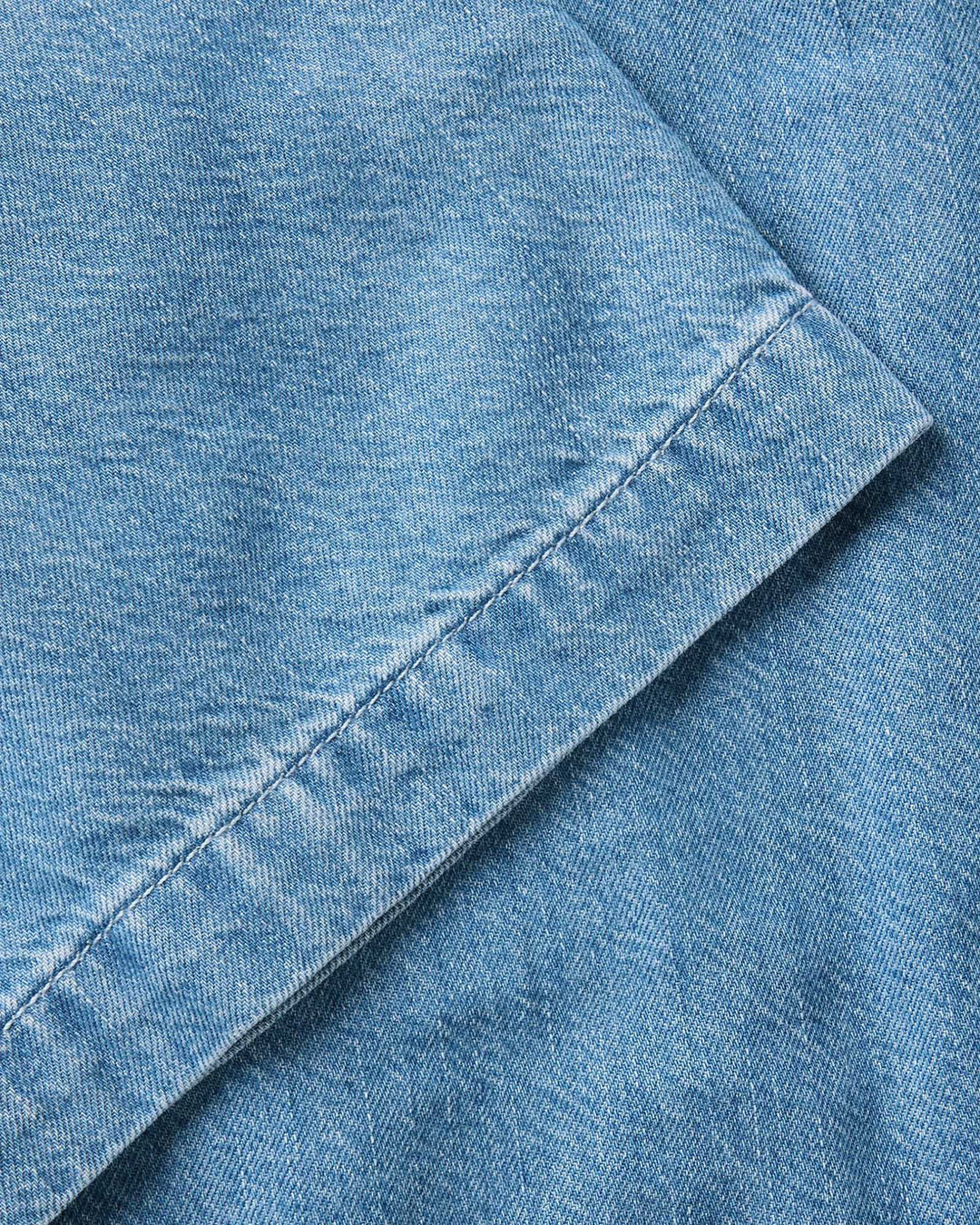 Close-up of The Gulf Shirt in Washed Indigo Twill fabric with a visible seam.