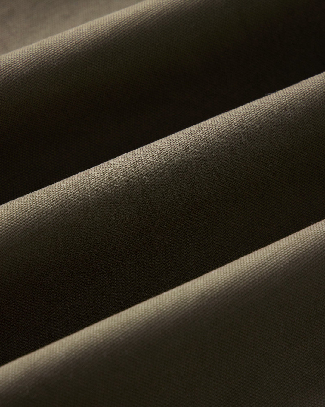 Close-up of draped fabric with a fine woven texture in a dark olive color.