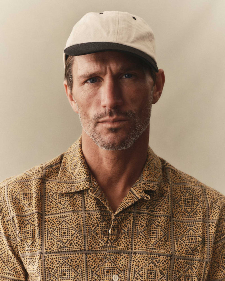 Man wearing a beige cap and The Hawthorne Shirt in Fennel Block Print against a neutral background