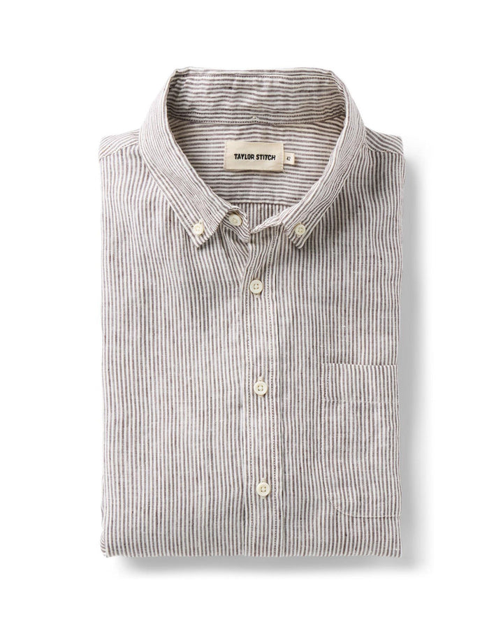 Folded burgundy and white striped shirt with button details on a white background