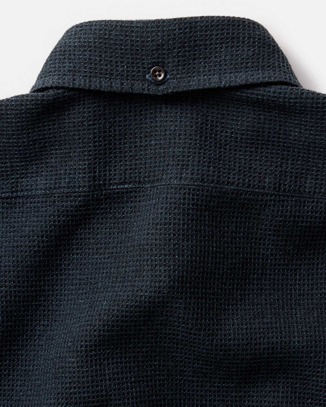 Close-up of the back collar of The Jack Shirt in Forest Waffle, showing a small button closure and the fabric weave against a light background.