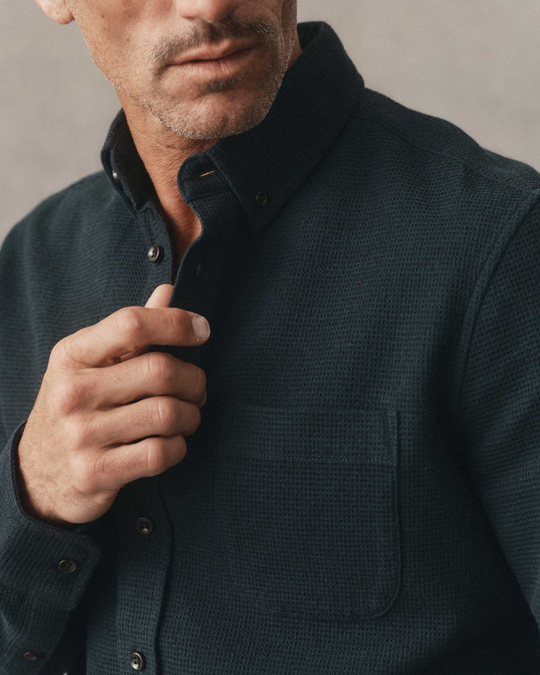 Close-up of a man wearing The Jack in Forest Waffle, adjusting the collar with his hand.
