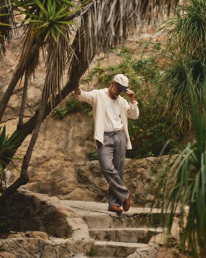 Man wearing the Jack Shirt in Vintage White walking up stone steps in a tropical setting with plants and rocks.