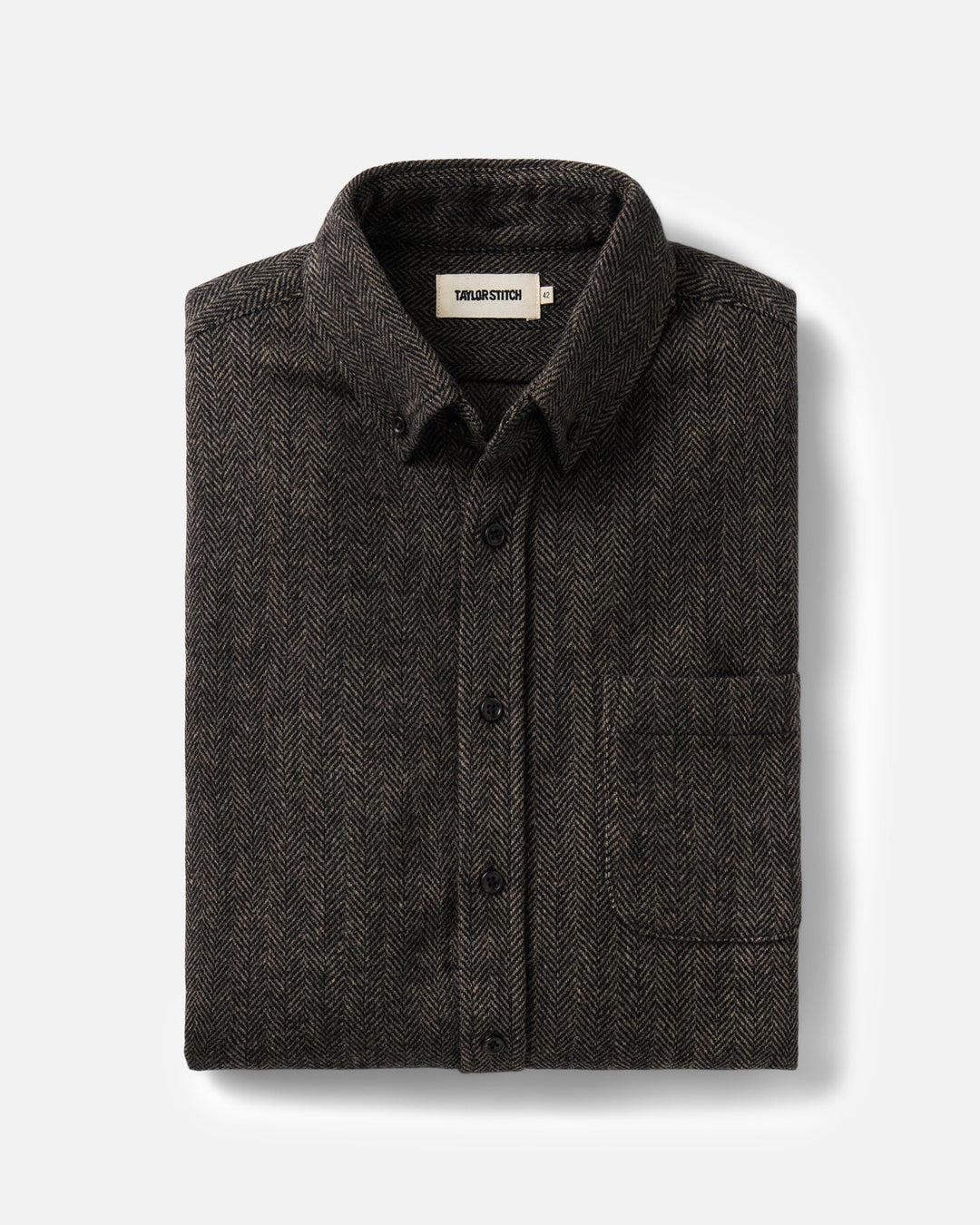 A dark brown herringbone pattern button-down shirt folded neatly on a light gray background. The shirt features a classic collar, button-down front, and a single chest pocket.