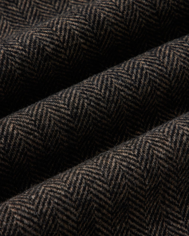 A close-up of draped fabric with a dark brown and black herringbone pattern.